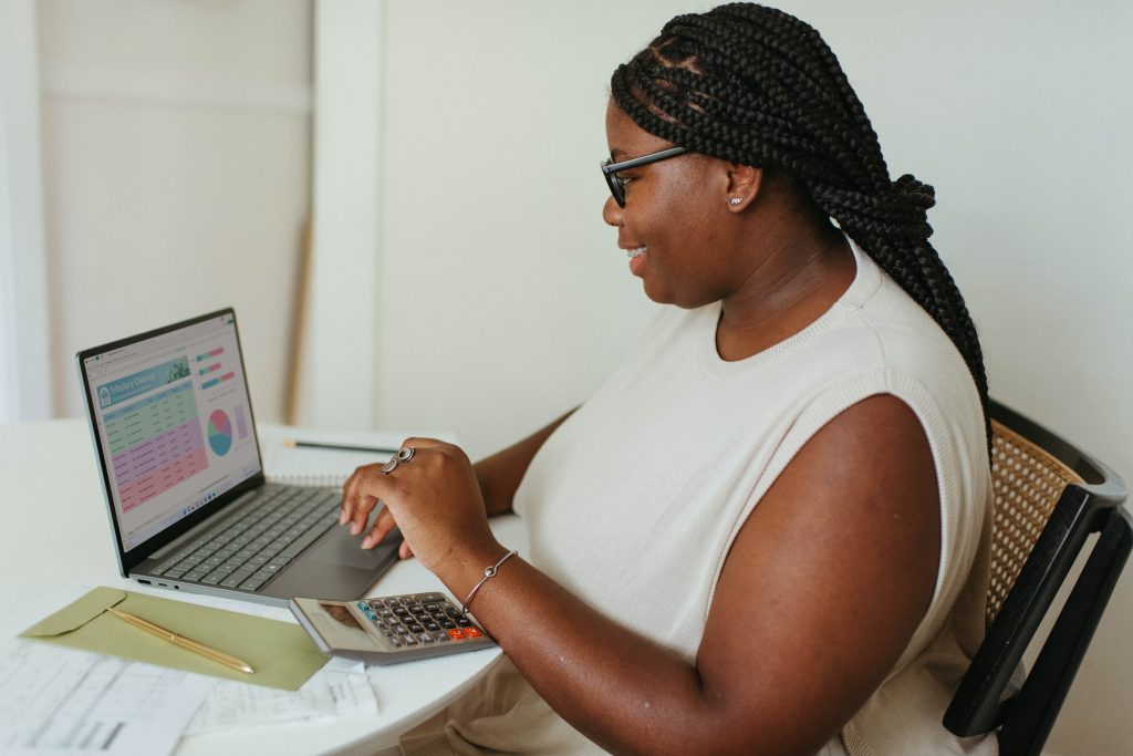 Black woman sits at a desk smiling at the pc monitor